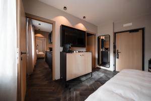 a hotel room with a bed and a flat screen tv at Schwarzer Adler - Concept Living in Vipiteno