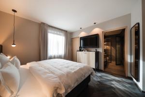 a hotel room with a bed and a flat screen tv at Schwarzer Adler - Concept Living in Vipiteno