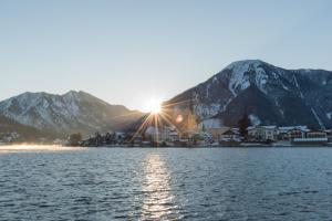 une ville sur l'eau avec des montagnes en arrière-plan dans l'établissement Althoff Seehotel Überfahrt, à Rottach-Egern