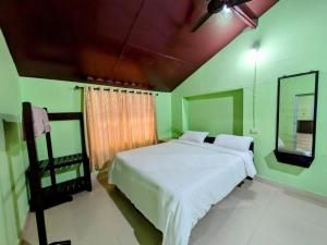 a bedroom with a white bed and a mirror at Thanmaya Homestay in Chikmagalūr