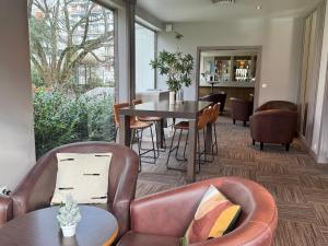 贝桑松Mercure Besancon Parc Micaud - Hotel & Bar的一间配备有皮椅和桌子的用餐室