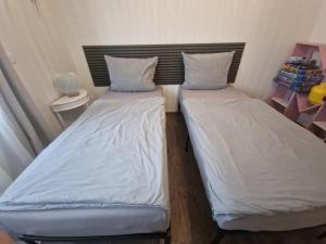 Cette chambre comprend 2 lits avec des draps et des oreillers blancs. dans l'établissement The Ferienwohnung, à Brême