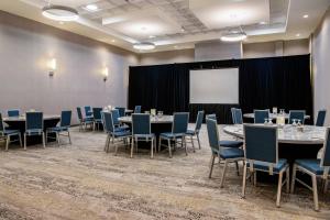 una sala conferenze con tavoli, sedie e schermo di Courtyard by Marriott Edmonton West a Edmonton