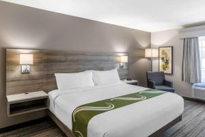 ein Hotelzimmer mit einem großen Bett und einem Stuhl in der Unterkunft Quality Inn & Suites Amsterdam in Fredericton