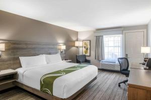 ein Hotelzimmer mit einem großen Bett und einem Schreibtisch in der Unterkunft Quality Inn & Suites Amsterdam in Fredericton