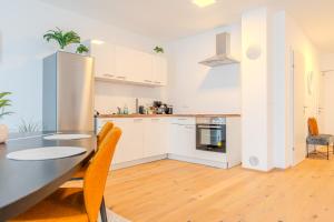 - une cuisine avec des placards blancs, une table et des chaises dans l'établissement Gneixendorf Exclusive Apartments, à Krems an der Donau