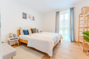 - une chambre blanche avec un grand lit et une fenêtre dans l'établissement Gneixendorf Exclusive Apartments, à Krems an der Donau