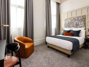 um quarto de hotel com uma cama e uma cadeira em The Municipal Hotel Liverpool - MGallery em Liverpool