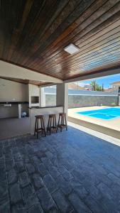 cocina y zona de comedor con taburetes y piscina en Casa 50m do mar, en Matinhos