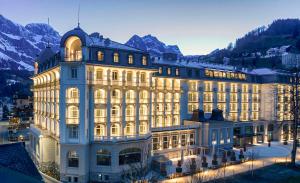 Kempinski Palace Engelberg في إنغيلبرغ: مبنى كبير عليه انوار امام الجبال