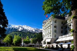 Kempinski Palace Engelberg في إنغيلبرغ: مبنى ابيض كبير مع جبل في الخلفية