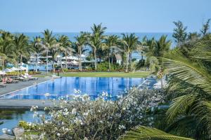 - une piscine dans un complexe avec des palmiers et l'océan dans l'établissement Muine Bay Resort, à Mui Ne