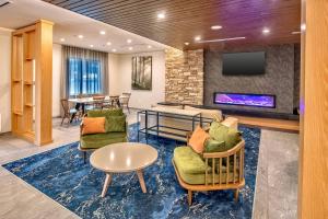 Fairfield Inn & Suites Fort Worth Northeast في هورست: لوبي فيه كراسي وتلفزيون وطاولة