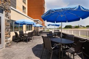 un patio con mesas y sillas y sombrillas azules en Fairfield Inn & Suites by Marriott Lancaster East at The Outlets, en Lancaster