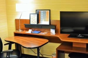 einen Schreibtisch mit einem TV und einem Hocker mit einer Lampe in der Unterkunft Fairfield Inn & Suites by Marriott Omaha Northwest in Omaha