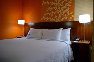 ein Schlafzimmer mit einem Bett mit weißer Bettwäsche und zwei Lampen in der Unterkunft Fairfield Inn & Suites by Marriott Stafford Quantico in Stafford