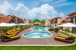 - une piscine avec des chaises longues et des parasols dans un complexe dans l'établissement Fairfield by Marriott Goa Benaulim, à Benaulim