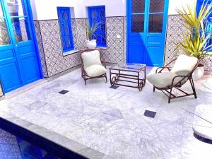 a patio with two chairs and a table and blue doors at Dar Saida in Sidi Bou Saïd