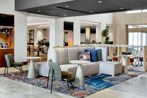 um átrio com um sofá, mesas e cadeiras em Detroit Metro Airport Marriott em Romulus