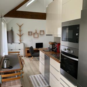 een keuken met witte kasten en een tafel in een kamer bij La Maisonnette de Senlis in Senlis