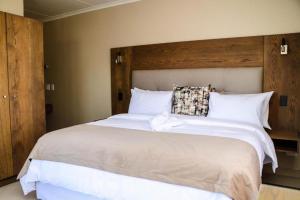 Schlafzimmer mit einem großen weißen Bett mit einem Kopfteil aus Holz in der Unterkunft Windhoek Gardens Boutique Hotel in Windhoek