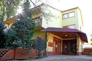 a yellow house with a fence and a tree at Appartementhaus Witzmann in Bad Vöslau