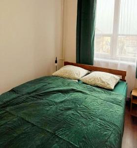 - une chambre avec un lit vert et une fenêtre dans l'établissement TomTom Hostel, à Cracovie