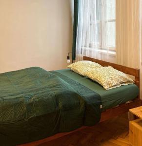 - une chambre avec un lit doté d'une couette verte et d'une fenêtre dans l'établissement TomTom Hostel, à Cracovie