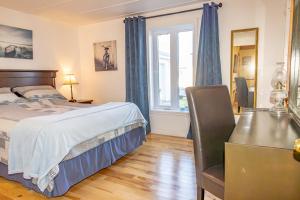 a bedroom with a bed and a desk and a window at Gite la Maison Rochefort in Baie-Sainte-Catherine