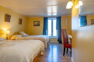 a room with three beds and a desk and a chair at Gite la Maison Rochefort in Baie-Sainte-Catherine