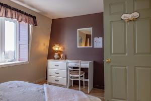 a bedroom with a desk and a bed and a window at Gite la Maison Rochefort in Baie-Sainte-Catherine