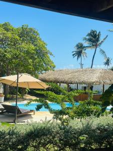 een resort met een zwembad en een parasol en een stoel bij Pousada Casa Caju Bangalows in Cumbuco