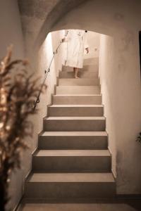 Eine Frau in einem weißen Kleid, die die Treppe hinuntergeht. in der Unterkunft Posthotel Lamm in Sterzing