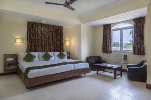 a bedroom with a bed and a chair and a window at Treebo Green Park in Mapusa