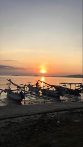 un gruppo di barche sulla spiaggia al tramonto di Gili Gede Homestay a Gili Gede