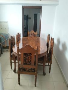 una mesa de madera con 4 sillas y un espejo en shirley cottage, en Daulatābād