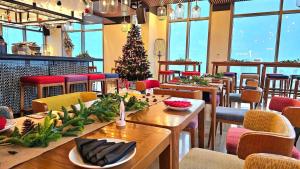 un restaurante con un árbol de Navidad, mesas y sillas en Wink Hotel Danang Centre - Dragon Bridge - 24hrs Stay, en Da Nang