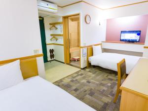 Toyoko Inn Hachinohe Ekimae في هاتشينوه: غرفة فندقية بسريرين وتلفزيون