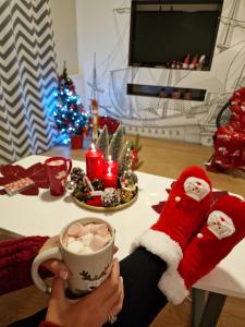 eine Person in einem Santa-Hut mit einer Tasse Kaffee in der Unterkunft Apartamenty Kajan in Jastrzębia Góra