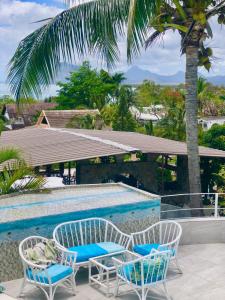 a swimming pool with two chairs and a table at Residence Ma Vie Là Ltee in Le Morne