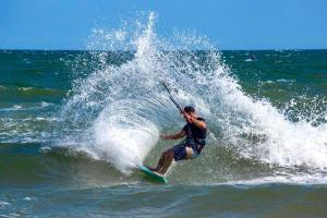 Un uomo che cavalca un'onda su una tavola da surf nell'oceano di Mana Mui Ne Beach Resort & Spa a Mui Ne