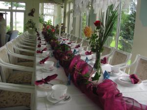 uma mesa longa com mesas brancas e cadeiras com flores em Natur& Waldhotel Johannesruh em Wesenberg