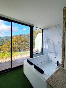 uma banheira branca num quarto com janelas em DOBAU village em Vieira do Minho