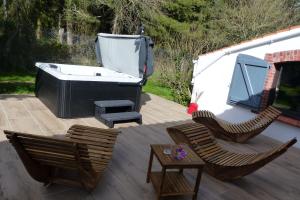 een patio met een bad, 2 stoelen en een tafel bij Nature et partage - Gîte tout équipé in Grand-Landes