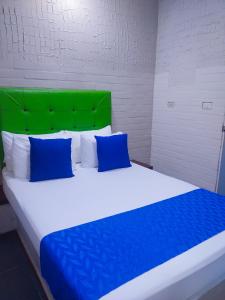 een groot bed met blauwe kussens en een groen hoofdeinde bij Casa Boston Inn in Barranquilla