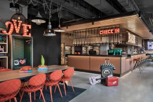 a restaurant with orange chairs and tables and a clock at Moxy Bremen in Bremen