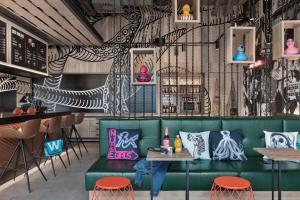 a room with a green couch and tables and a bar at Moxy Bremen in Bremen