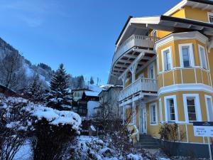 uma casa amarela com neve no chão em das zellersee em Zell am See