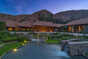 une maison avec un étang en face d'une montagne dans l'établissement Tambo del Inka, a Luxury Collection Resort & Spa, Valle Sagrado, à Urubamba