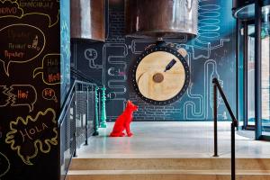 un gato rojo sentado frente a una pared con un reloj en Moxy Warsaw Praga, en Varsovia